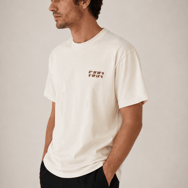 Hombre con camiseta marfil de Acusmagna. con bordado de coordenadas en granate elegante.